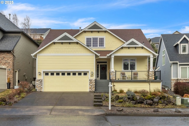 craftsman inspired home featuring stone siding, asphalt driveway, a porch, and an attached garage