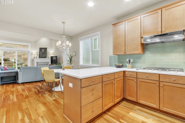 kitchen with under cabinet range hood, white gas stovetop, light wood-type flooring, open floor plan, and light countertops