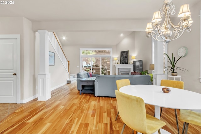 dining space with light wood-style floors, a fireplace, stairway, a chandelier, and recessed lighting