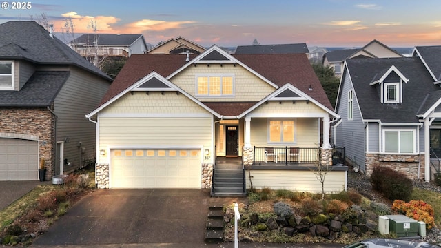 craftsman-style home featuring stone siding, asphalt driveway, covered porch, and a residential view