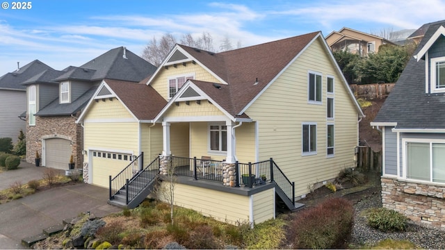 craftsman-style home with a porch, concrete driveway, a garage, and stone siding