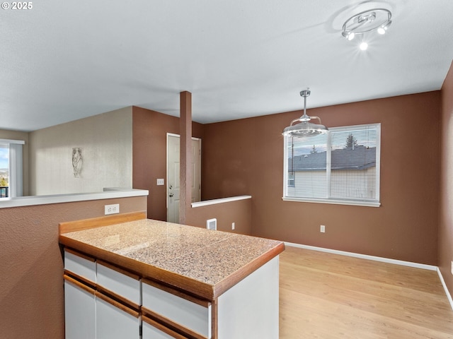 kitchen with light hardwood / wood-style floors, white cabinetry, and pendant lighting