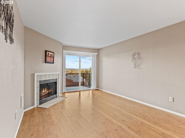 unfurnished living room featuring a tile fireplace and light hardwood / wood-style flooring