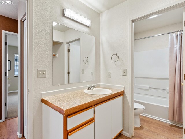 full bathroom with shower / bath combo with shower curtain, toilet, vanity, and wood-type flooring