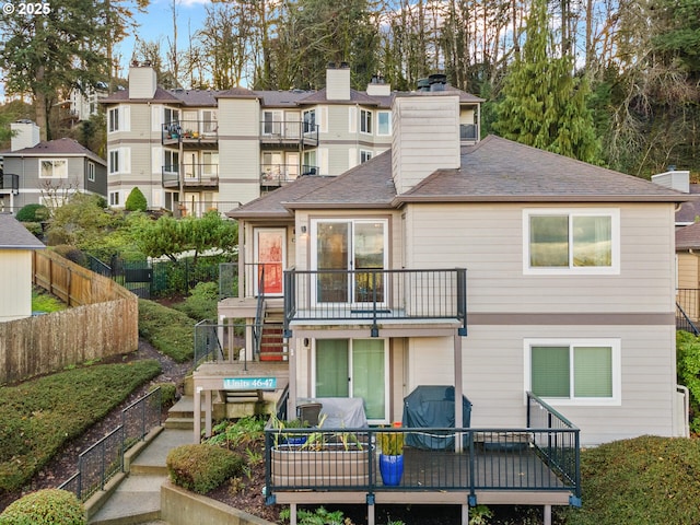 back of property featuring a balcony and a wooden deck