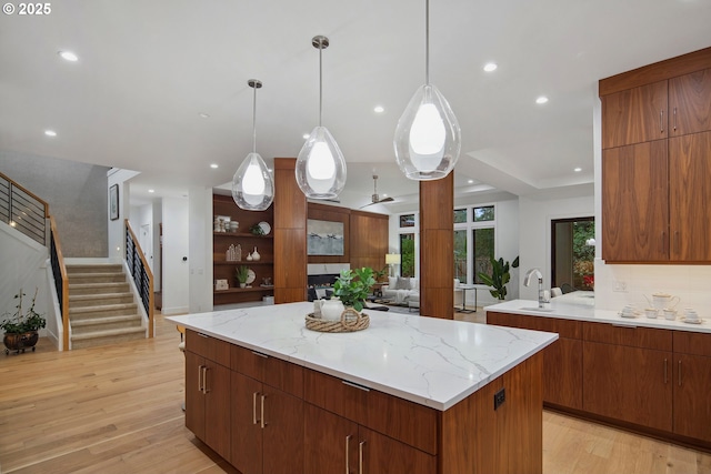 kitchen with light wood-type flooring, pendant lighting, a center island, and tasteful backsplash