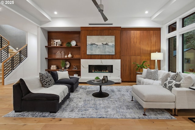 living room featuring light hardwood / wood-style floors, a high end fireplace, and built in features