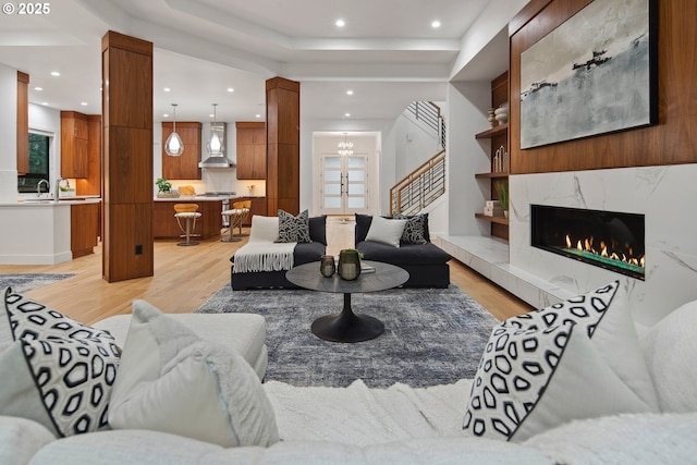 living room featuring light hardwood / wood-style floors, an inviting chandelier, and a premium fireplace