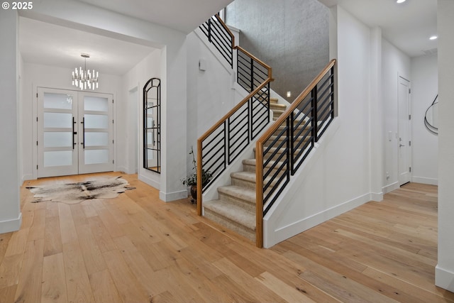 entrance foyer featuring light wood-type flooring, french doors, and a chandelier