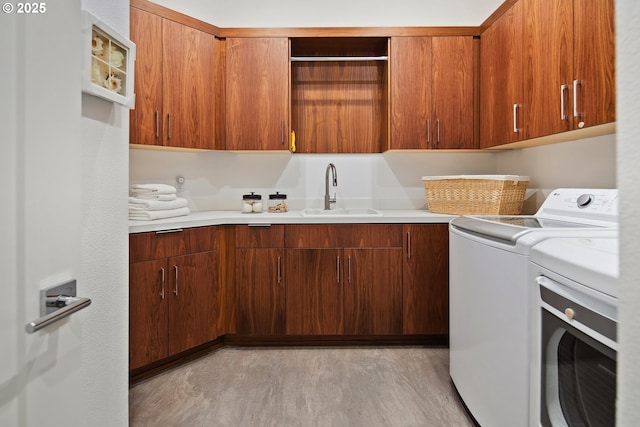 laundry area featuring sink, separate washer and dryer, light hardwood / wood-style floors, and cabinets