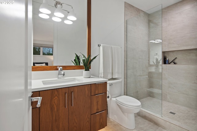 bathroom featuring tiled shower, toilet, tile patterned flooring, and vanity