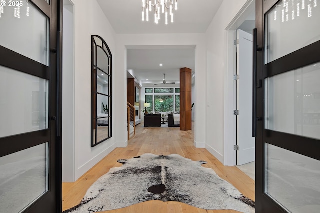 corridor with a chandelier and light wood-type flooring