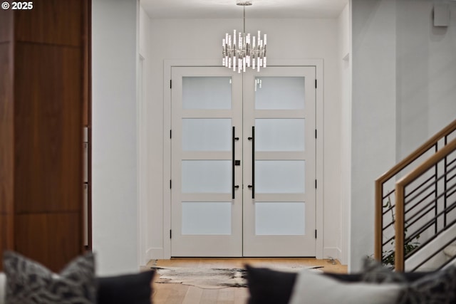 foyer entrance featuring a notable chandelier, french doors, and hardwood / wood-style floors