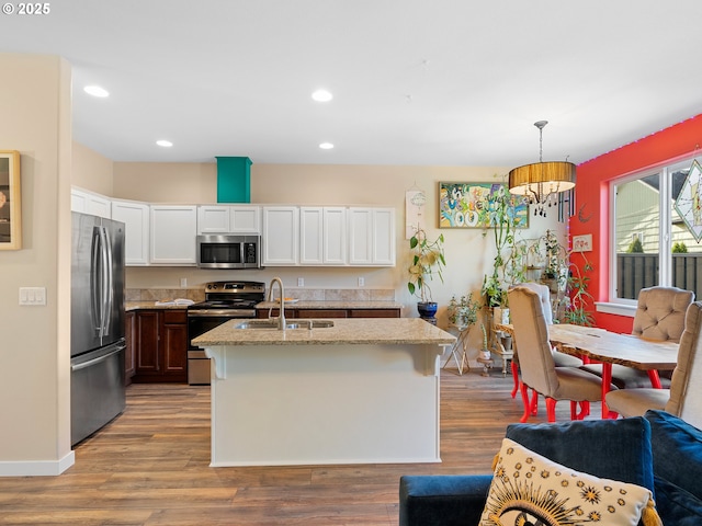 kitchen featuring pendant lighting, sink, appliances with stainless steel finishes, an island with sink, and white cabinets