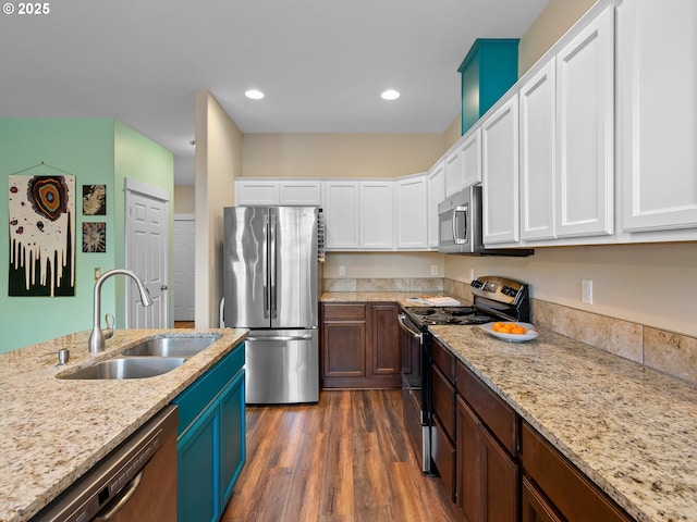 kitchen featuring sink, white cabinets, light stone counters, stainless steel appliances, and dark wood-type flooring