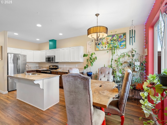 dining area with dark wood-type flooring, an inviting chandelier, and sink