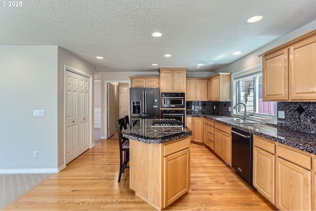 10939 SE Valley Way, Happy Valley, OR 97086 - kitchen with black appliances, light brown cabinets, light wood-type flooring, a kitchen breakfast bar, and a kitchen island