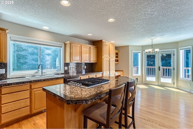 10939 SE Valley Way, Happy Valley, OR 97086 - kitchen featuring tile counters, stainless steel gas cooktop, light wood-style flooring, a chandelier, and backsplash