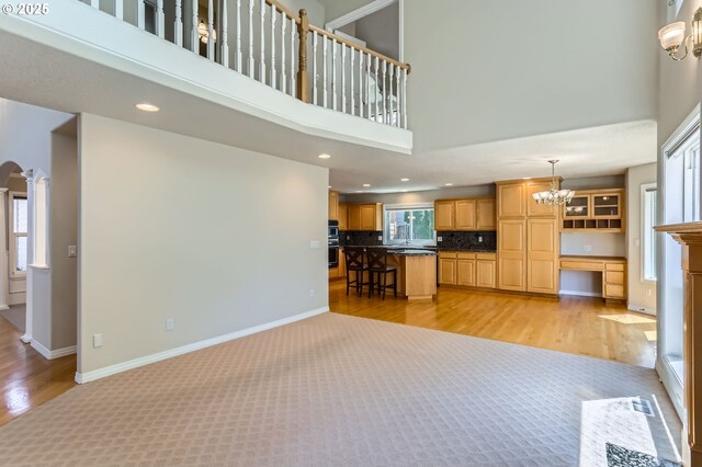 10939 SE Valley Way, Happy Valley, OR 97086 - unfurnished living room featuring a high ceiling, a chandelier, light wood-style floors, arched walkways, and recessed lighting
