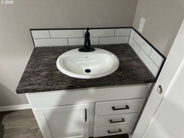 bathroom with vanity, decorative backsplash, wood finished floors, and baseboards