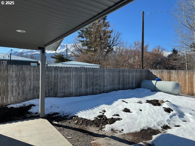 yard covered in snow with a fenced backyard