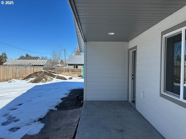 snow covered patio featuring fence