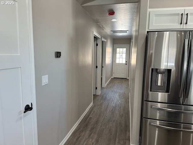 hallway featuring baseboards and dark wood-style flooring