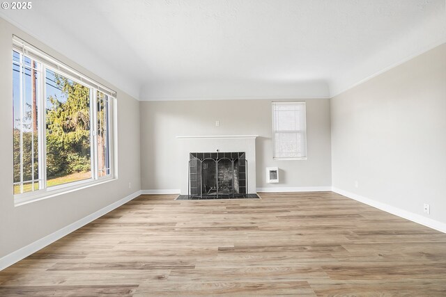 unfurnished living room with heating unit, a fireplace, and light hardwood / wood-style flooring