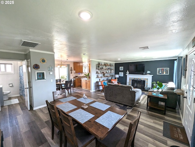 96335 Dawson Rd, Brookings, OR 97415 - dining area featuring visible vents, dark wood finished floors, crown molding, and a fireplace