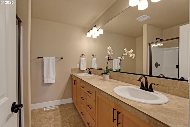 full bath featuring a shower with door, double vanity, baseboards, and tile patterned flooring