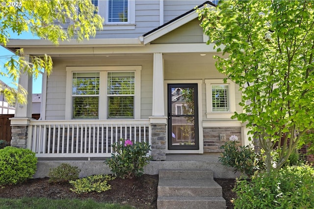 entrance to property featuring covered porch and stone siding