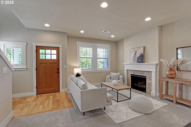 carpeted living area featuring a textured ceiling, recessed lighting, baseboards, a fireplace, and wood finished floors