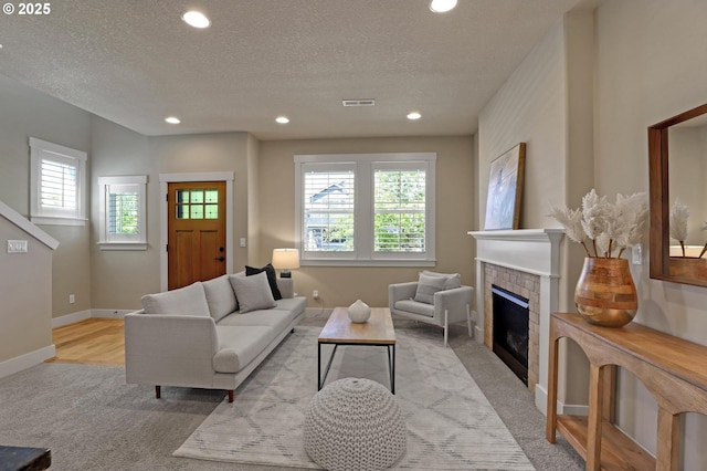 living area featuring light carpet, plenty of natural light, a fireplace, recessed lighting, and a textured ceiling