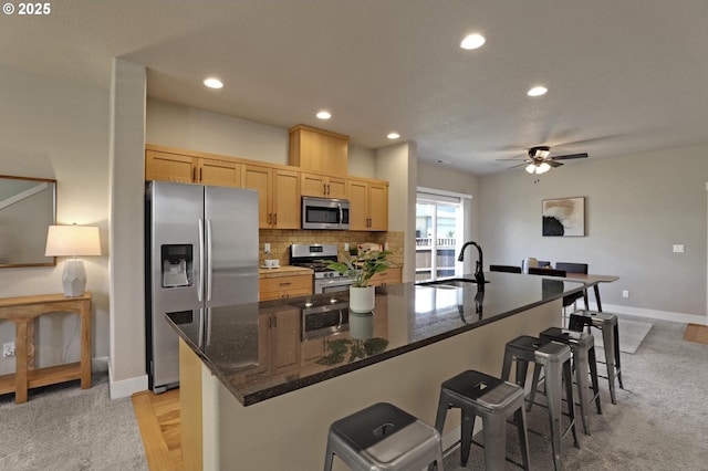 kitchen with stainless steel appliances, a sink, recessed lighting, light brown cabinets, and a large island
