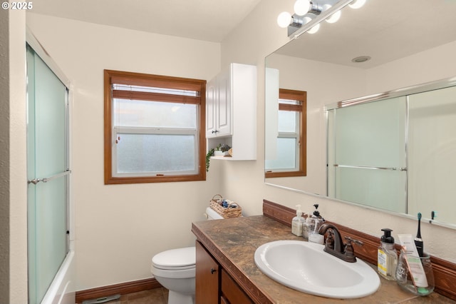 bathroom with plenty of natural light, toilet, vanity, and enclosed tub / shower combo