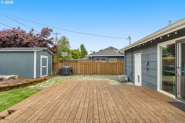 wooden deck with a shed, fence, and an outdoor structure