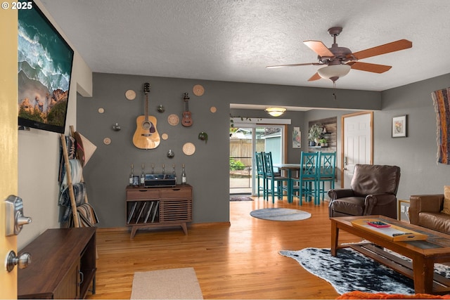 living area featuring light wood-style flooring, a ceiling fan, and a textured ceiling