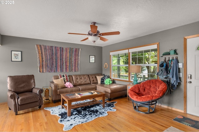 living area with wood finished floors, ceiling fan, a textured ceiling, and baseboards