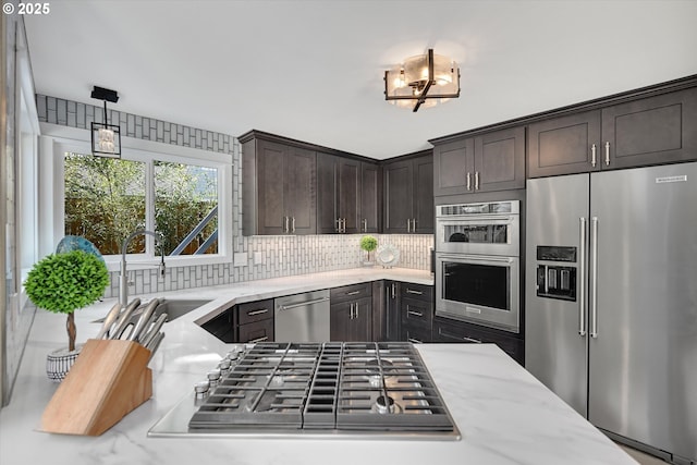 15525 SW Hearth Ct, Beaverton, OR 97007 - kitchen with appliances with stainless steel finishes, a sink, dark brown cabinetry, tasteful backsplash, and light stone counters