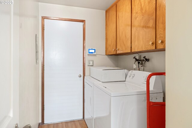 laundry room with washer and dryer, light wood finished floors, and cabinet space