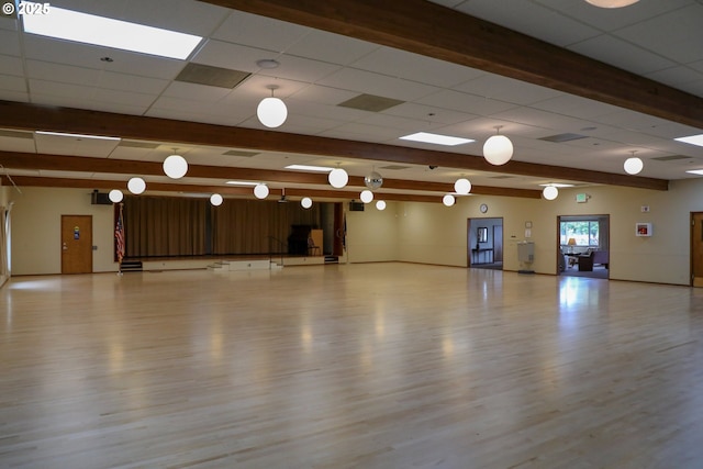 miscellaneous room featuring beamed ceiling, a drop ceiling, and wood finished floors