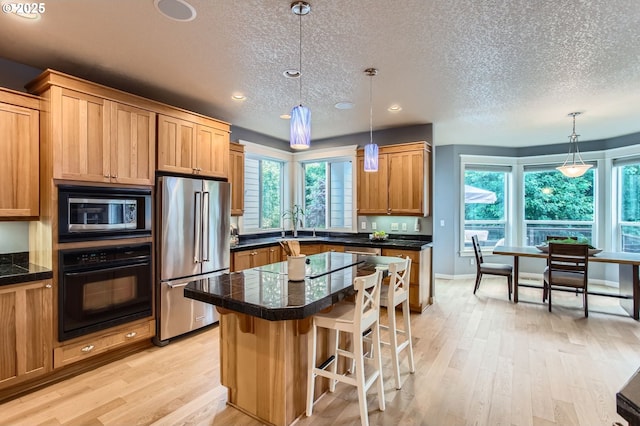 10445 SW 141st Ave, Beaverton, OR 97008 - kitchen with stainless steel appliances, tile counters, light wood-type flooring, a breakfast bar area, and a textured ceiling