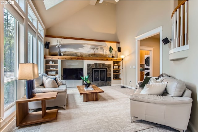 10445 SW 141st Ave, Beaverton, OR 97008 - living area featuring stacked washer / drying machine, high vaulted ceiling, plenty of natural light, a tile fireplace, and carpet floors