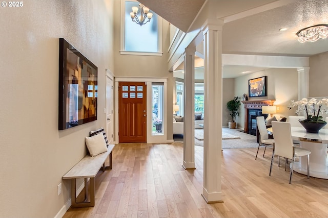10445 SW 141st Ave, Beaverton, OR 97008 - foyer featuring ornate columns, light wood-style flooring, a glass covered fireplace, and healthy amount of natural light