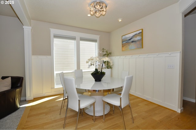 10445 SW 141st Ave, Beaverton, OR 97008 - dining room featuring light wood finished floors, a wainscoted wall, a chandelier, ornate columns, and a decorative wall