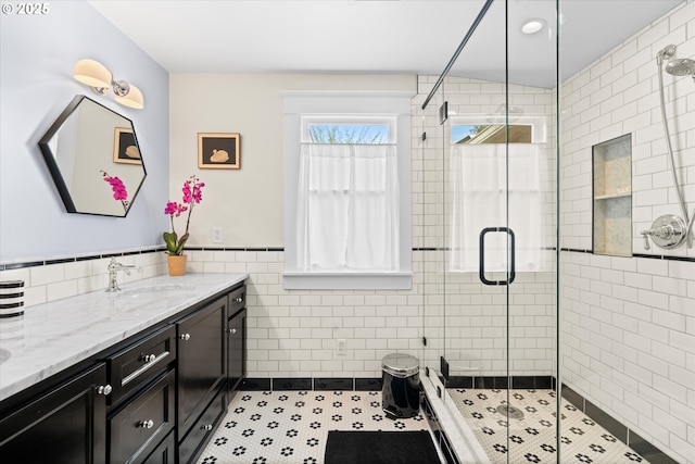 bathroom with tile walls, vanity, a shower stall, and a wainscoted wall