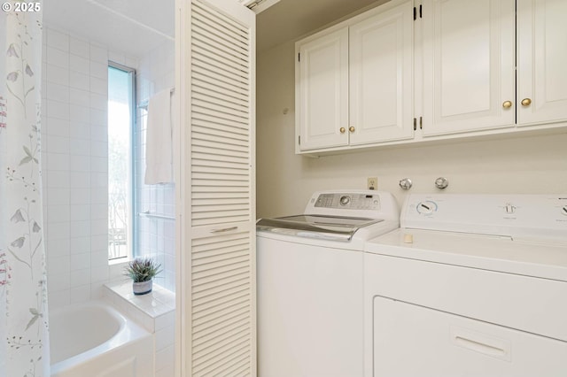 washroom featuring independent washer and dryer, cabinet space, and a healthy amount of sunlight