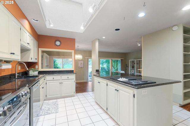 kitchen with stove, sink, stovetop, white cabinets, and a center island