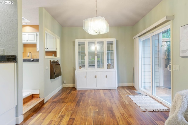 unfurnished dining area featuring a chandelier and dark hardwood / wood-style floors