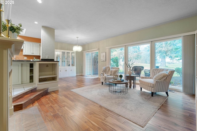 living room featuring light hardwood / wood-style flooring, a textured ceiling, and an inviting chandelier